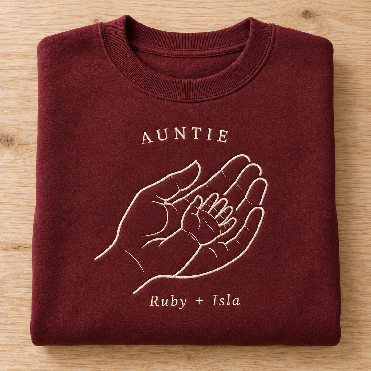 Handful of Love personalized Auntie hands design; Maroon sweatshirt mockup, personalization detail; sample text AUNTIE / Ruby + Isla