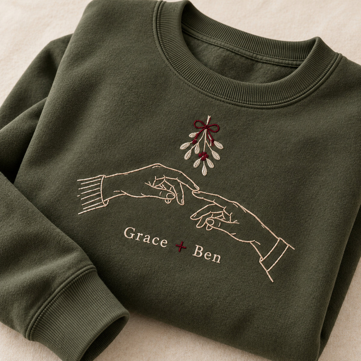 Hands Under Mistletoe personalized Christmas hands design; Military Green sweatshirt mockup, personalization detail; sample text Grace + Ben
