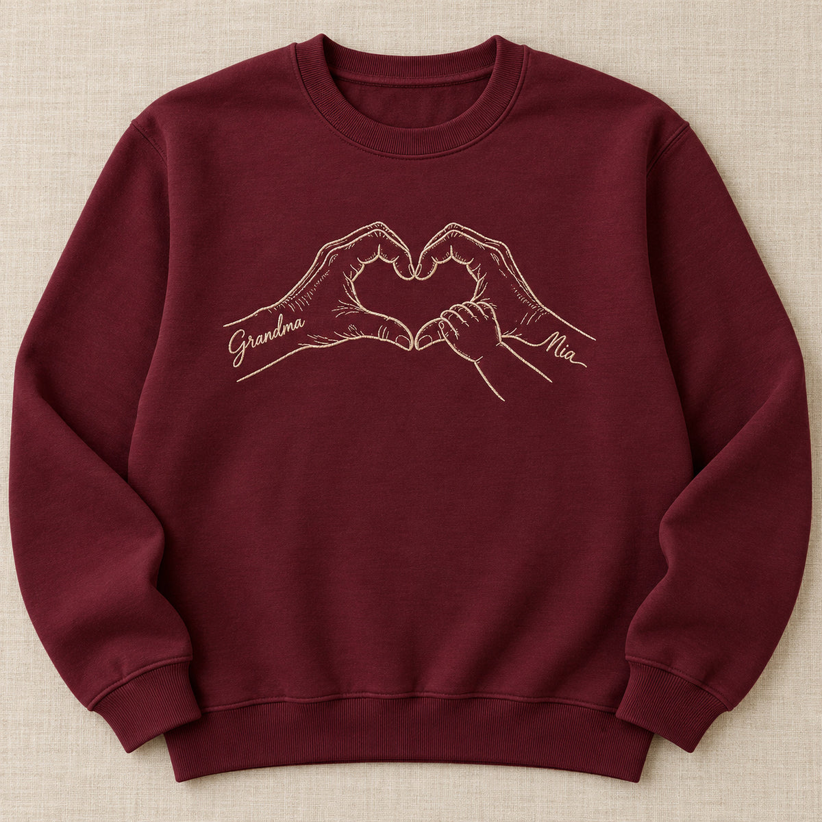 Heart of Grandma personalized Grandma hands design; Maroon sweatshirt mockup, hero; sample text Grandma / Mia