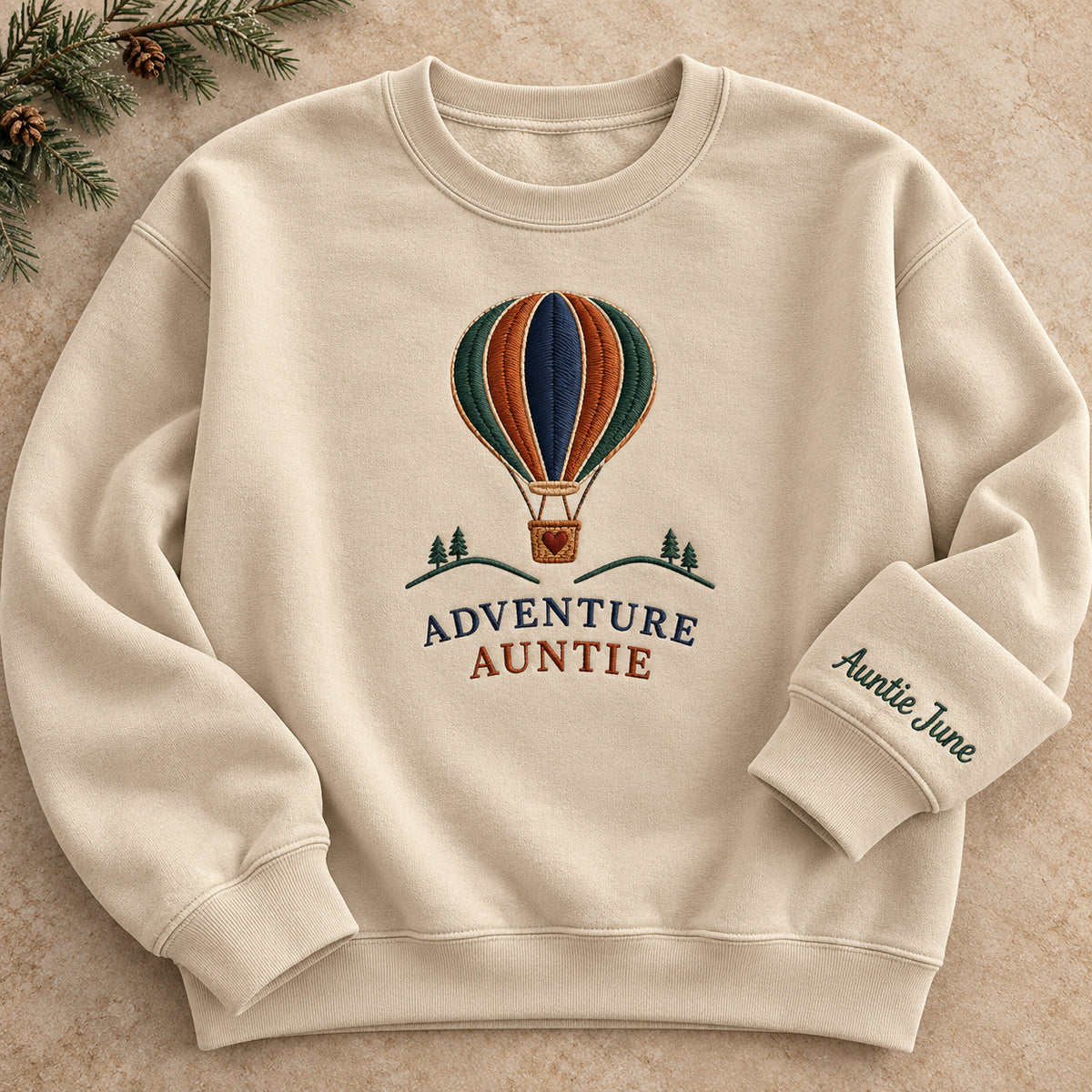 Adventure Auntie sweatshirt concept mockup featuring a hot-air balloon above small trees and hills, sample personalization Auntie June, hero view