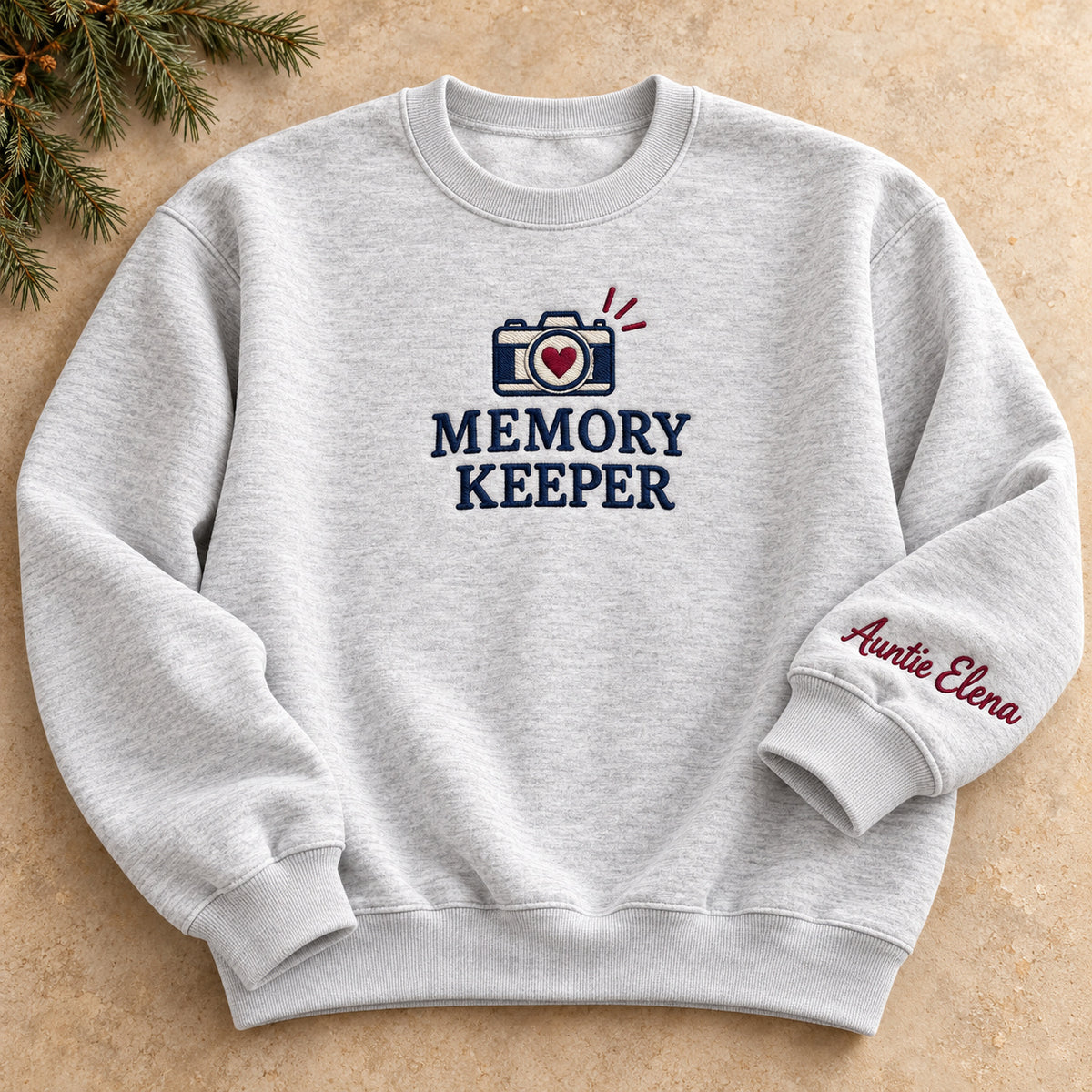 Auntie Memory Keeper sweatshirt concept mockup featuring a camera with a heart-shaped lens, sample personalization Auntie Elena, hero view