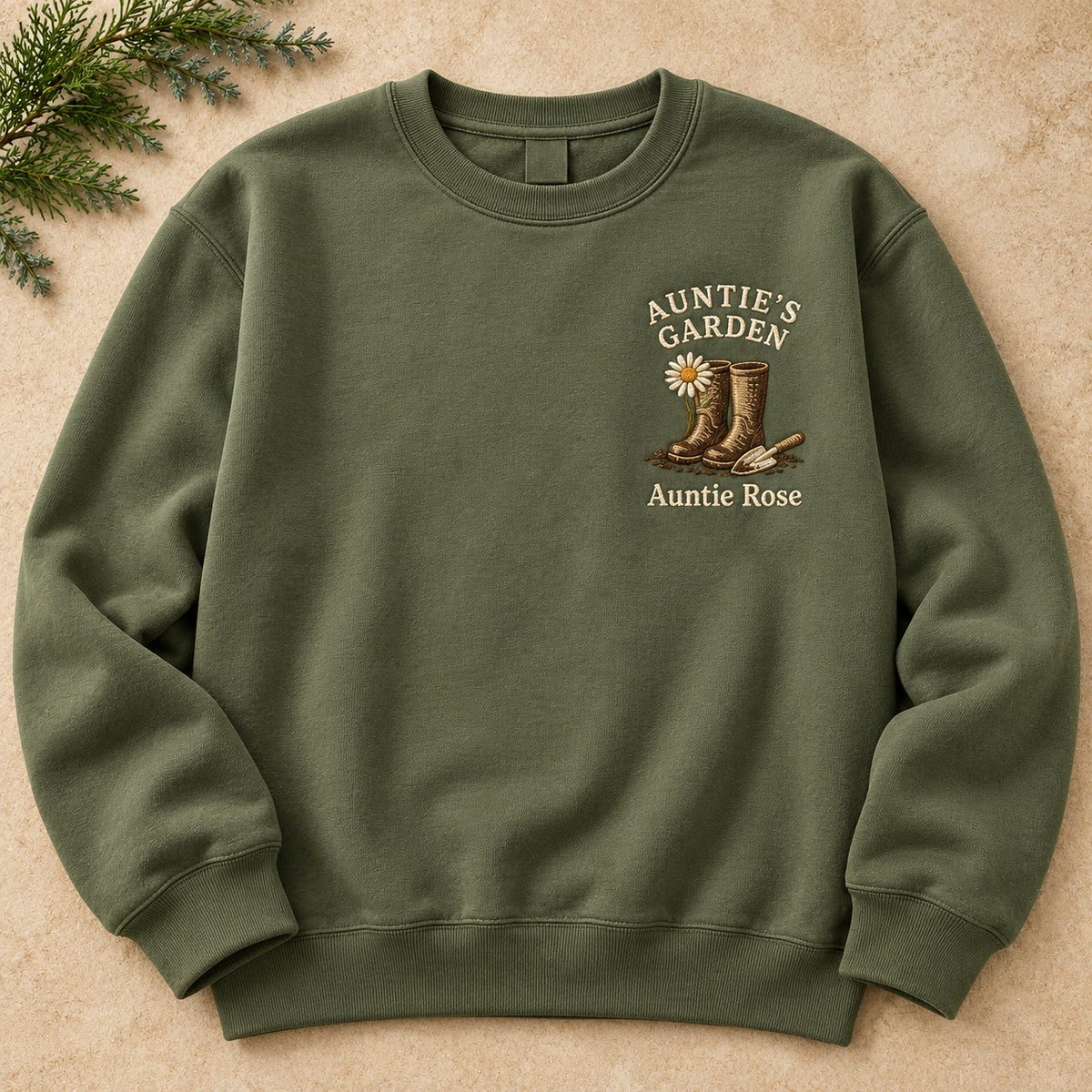 Auntie's Garden sweatshirt concept mockup featuring garden boots, a daisy and a hand trowel, sample personalization Auntie Rose, hero view