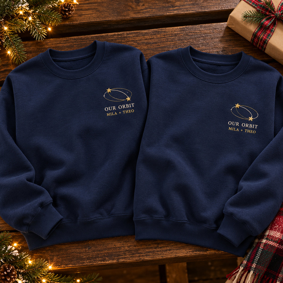 Our Orbit sweatshirt concept mockup featuring two stars linked by orbit lines, sample personalization MILA + THEO, hero view