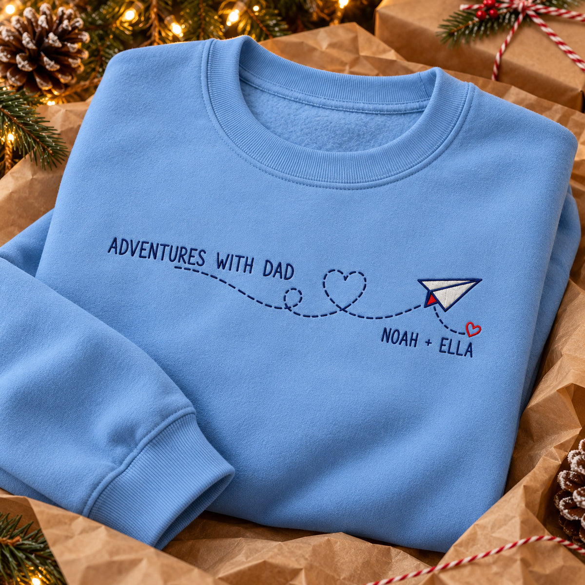Adventures with Dad sweatshirt concept mockup featuring a paper airplane with a heart-shaped flight trail, sample personalization NOAH + ELLA, personalization view