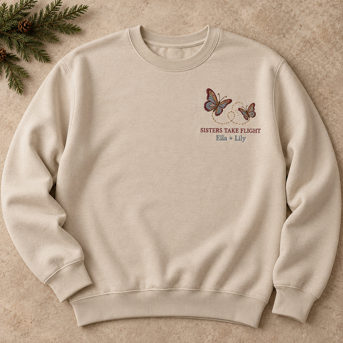 Sisters Take Flight sweatshirt concept mockup featuring two butterflies with a looping flight path, sample personalization Ella + Lily, hero view
