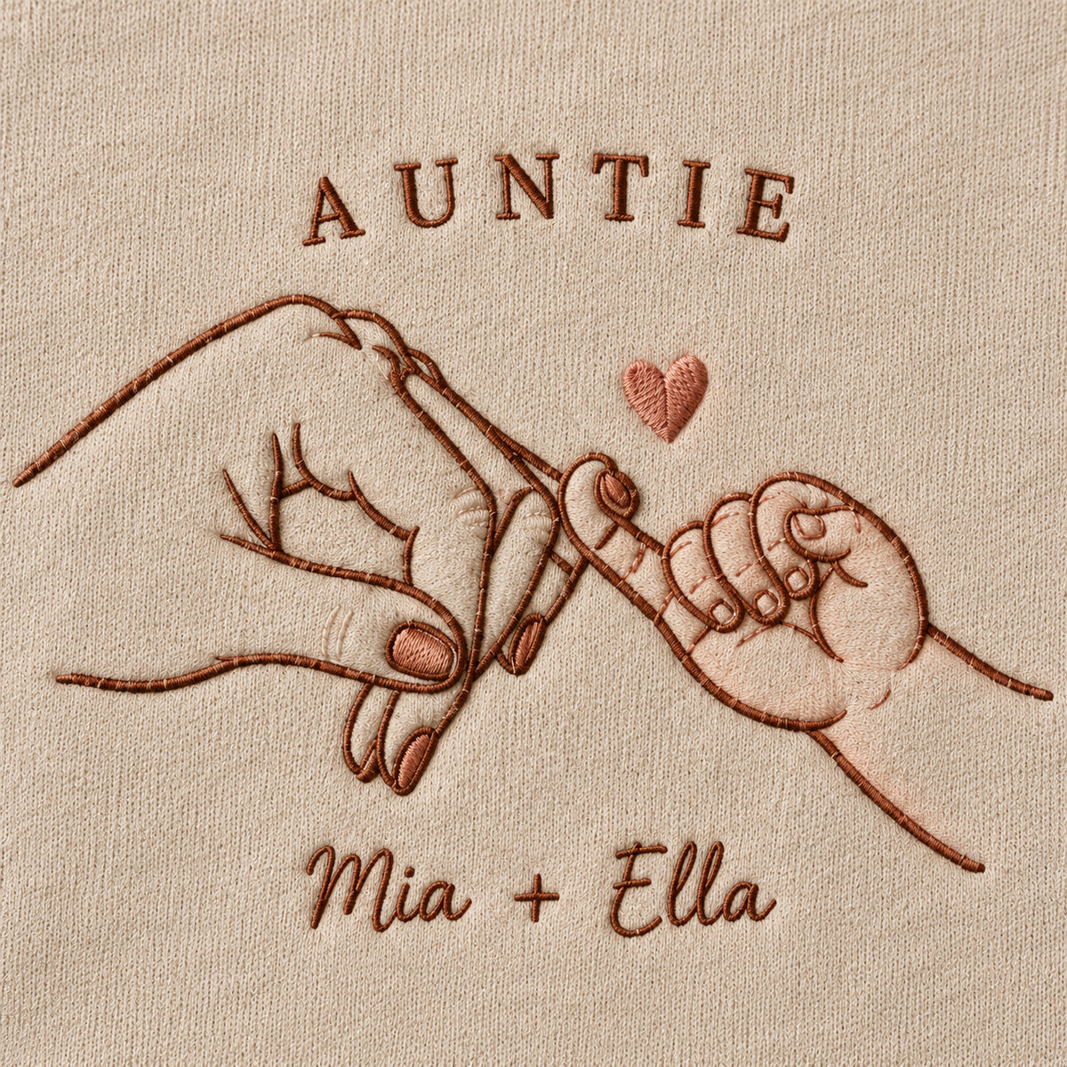 Pinky Adventure personalized Auntie hands design; Sand sweatshirt mockup, embroidery detail; sample text AUNTIE / Mia + Ella