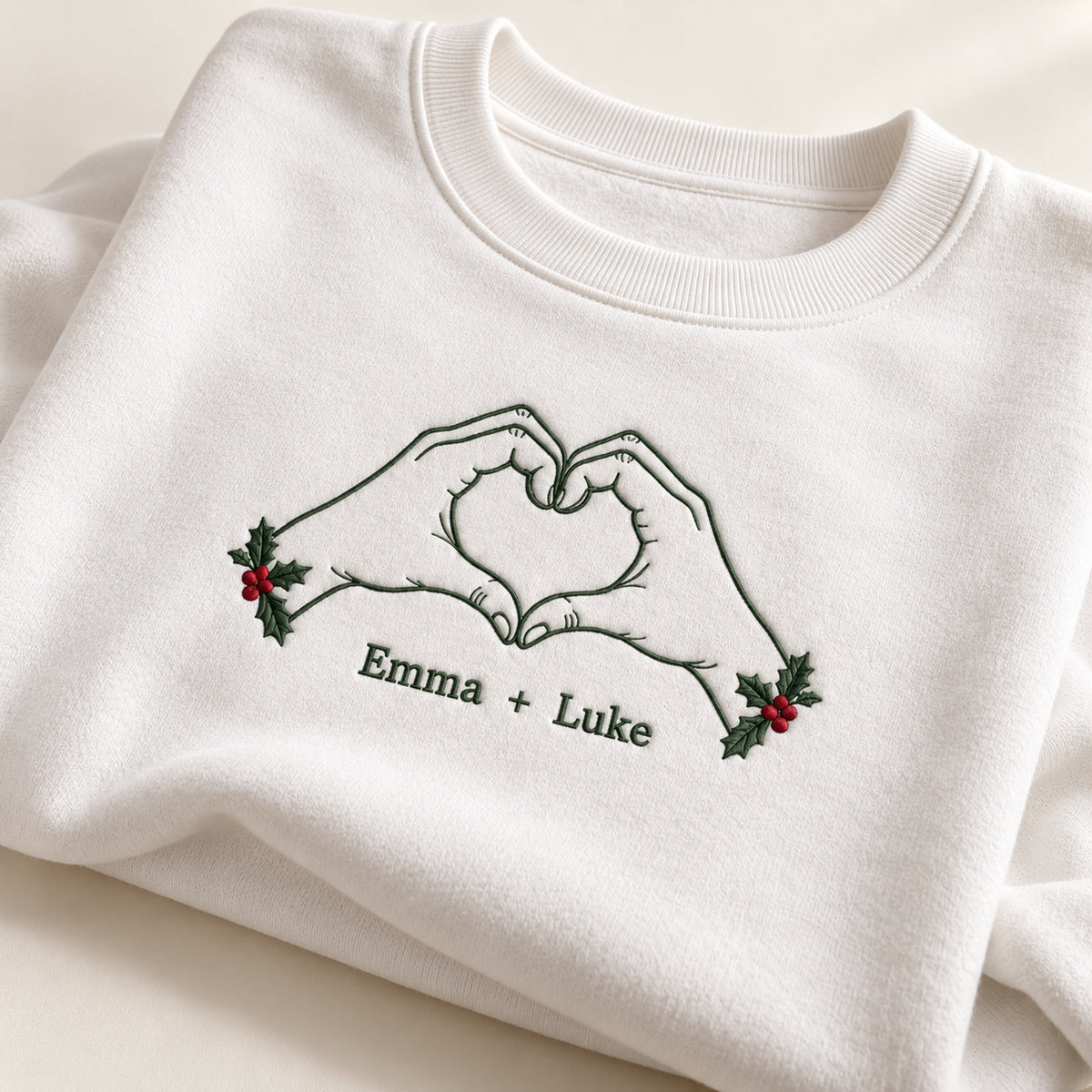 Christmas Heart Hands personalized Christmas hands design; White sweatshirt mockup, personalization detail; sample text Emma + Luke