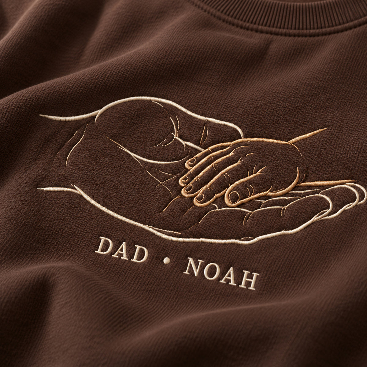 Safe In My Palm personalized Dad hands design; Chocolate sweatshirt mockup, embroidery detail; sample text DAD • NOAH
