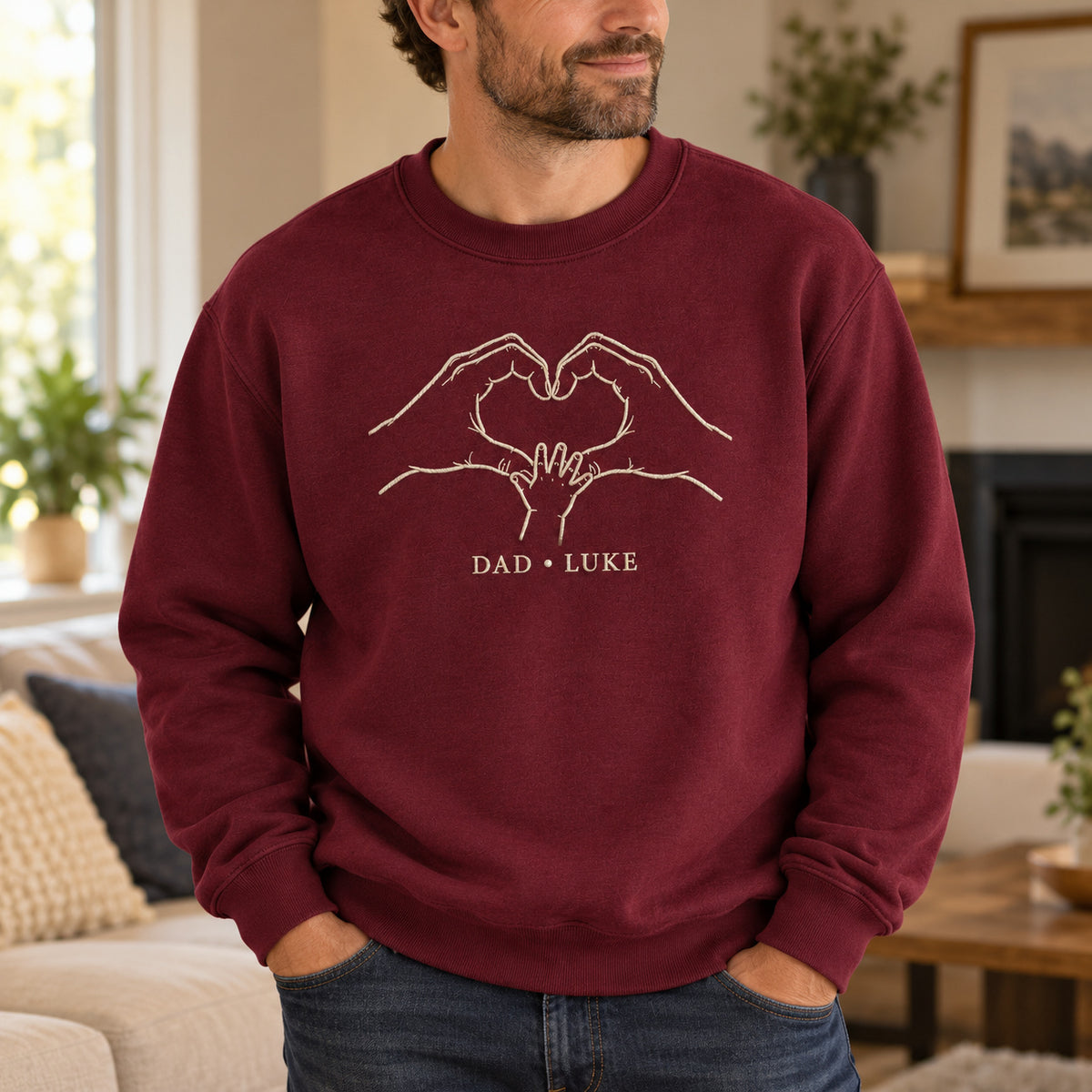 Heart In Our Hands personalized Dad hands design; Maroon sweatshirt mockup, lifestyle; sample text DAD • LUKE