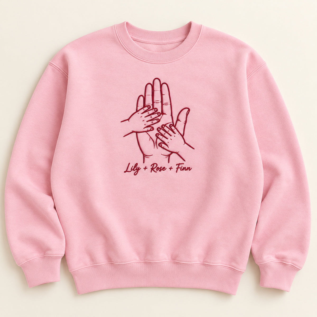 Held by Love personalized Family hands design; Light Pink sweatshirt mockup, hero; sample text Lily + Rose + Finn