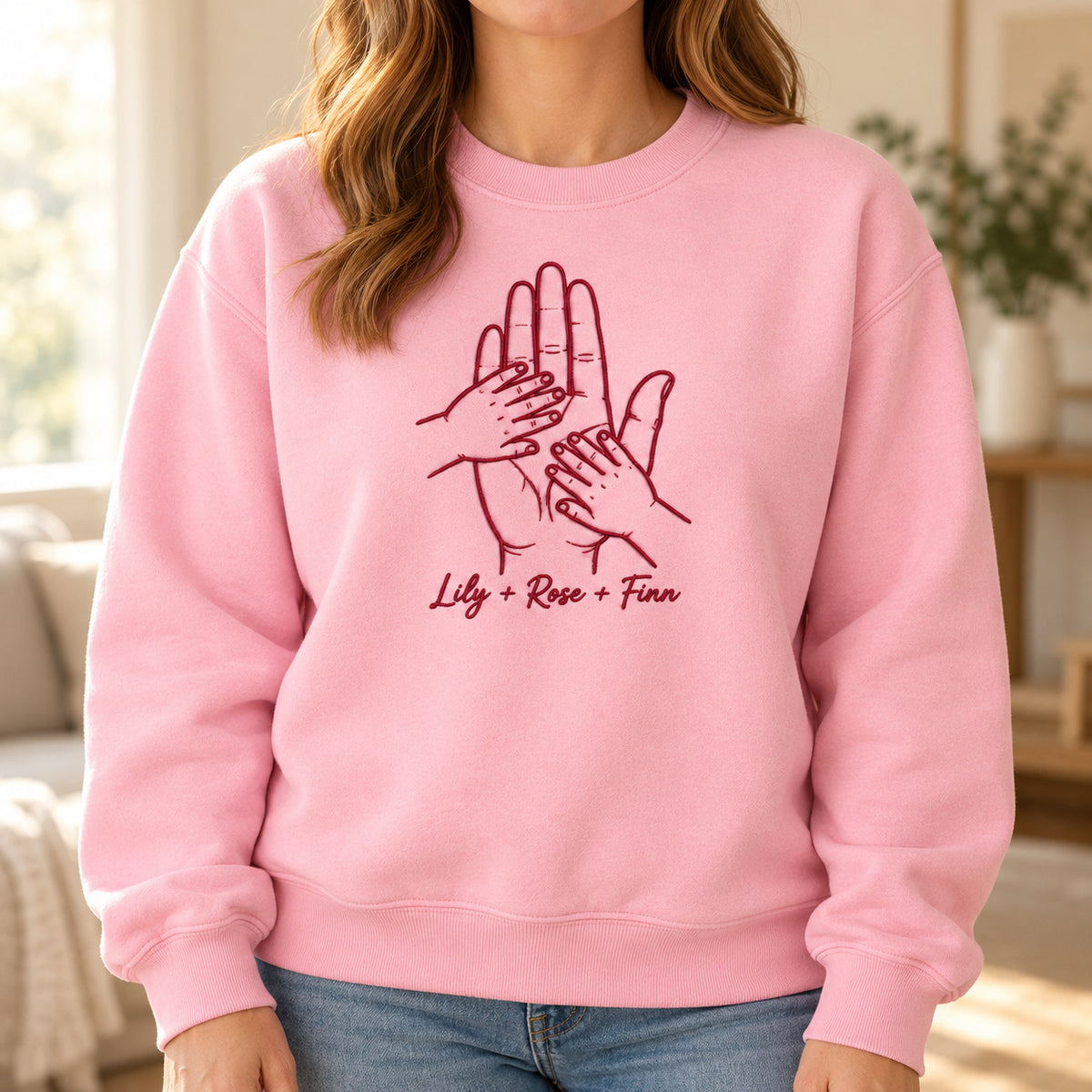 Held by Love personalized Family hands design; Light Pink sweatshirt mockup, lifestyle; sample text Lily + Rose + Finn