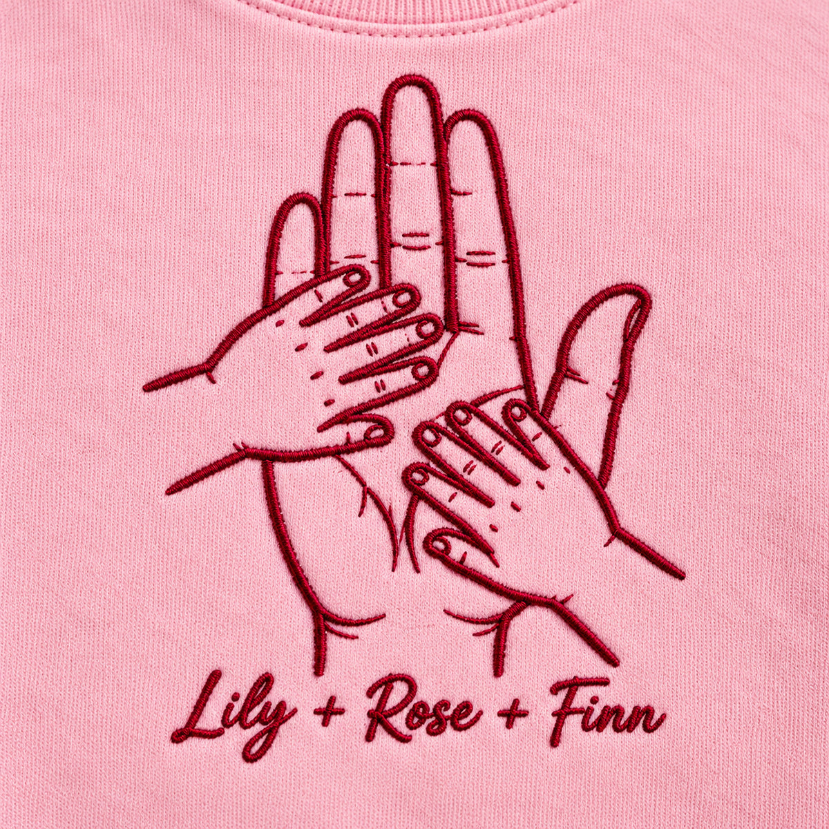 Held by Love personalized Family hands design; Light Pink sweatshirt mockup, embroidery detail; sample text Lily + Rose + Finn