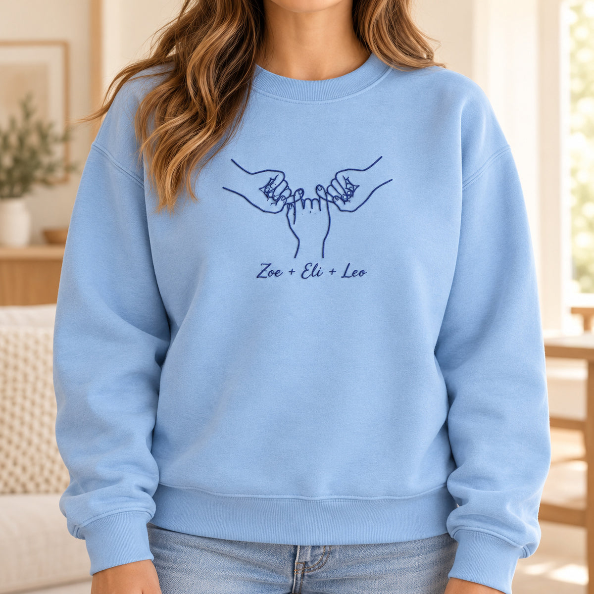 Our Promise personalized Family hands design; Light Blue sweatshirt mockup, lifestyle; sample text Zoe + Eli + Leo