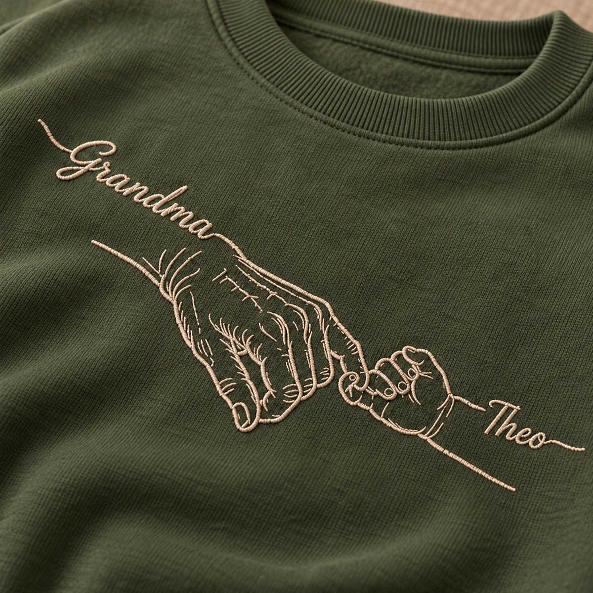 Grandma's Promise personalized Grandma hands design; Military Green sweatshirt mockup, embroidery detail; sample text Grandma / Theo