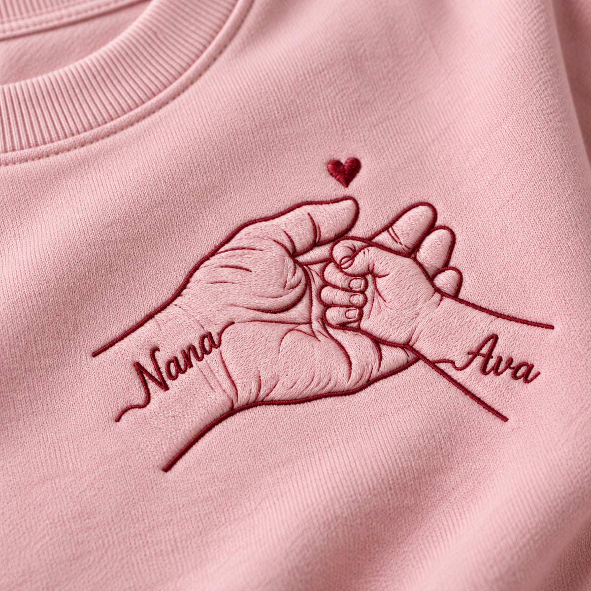 Held Through Life personalized Grandma hands design; Light Pink sweatshirt mockup, embroidery detail; sample text Nana / Ava