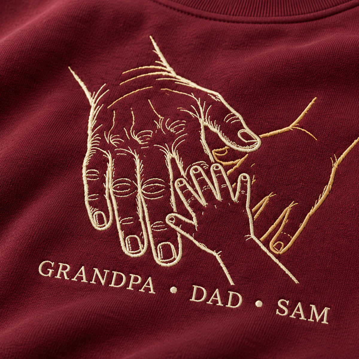 Three Generations personalized Grandpa hands design; Maroon sweatshirt mockup, embroidery detail; sample text GRANDPA • DAD • SAM