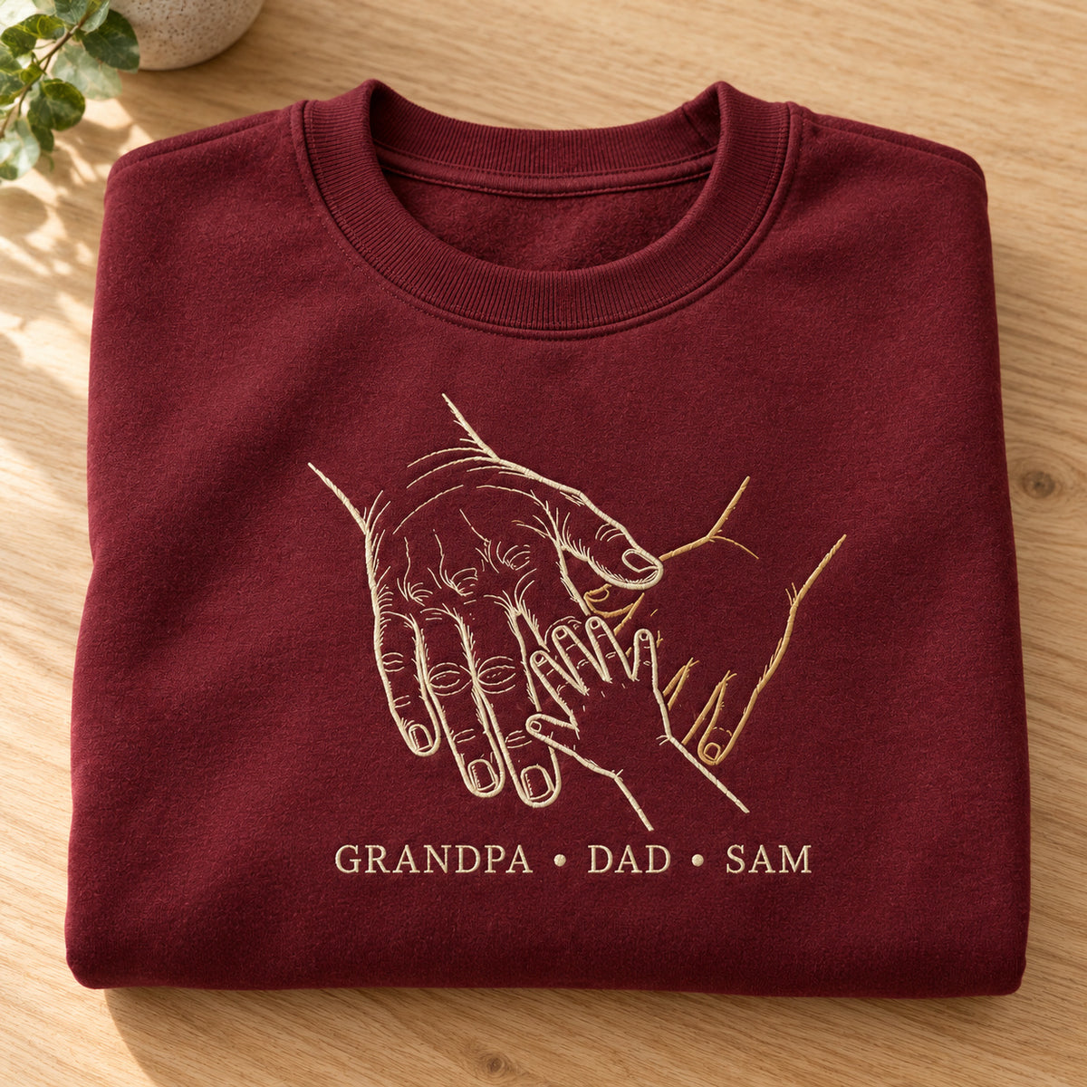 Three Generations personalized Grandpa hands design; Maroon sweatshirt mockup, personalization detail; sample text GRANDPA • DAD • SAM