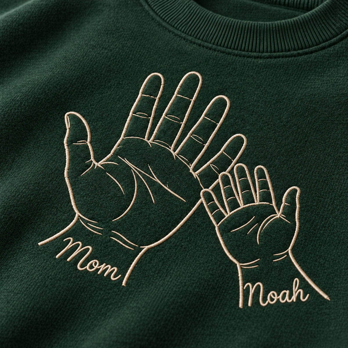Palm to Palm personalized Mom hands design; Forest Green sweatshirt mockup, embroidery detail; sample text Mom / Noah