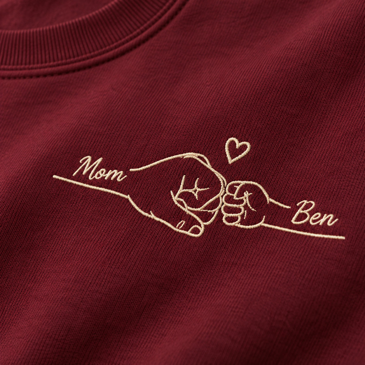 First Fist Bump personalized Mom hands design; Maroon sweatshirt mockup, embroidery detail; sample text Mom / Ben
