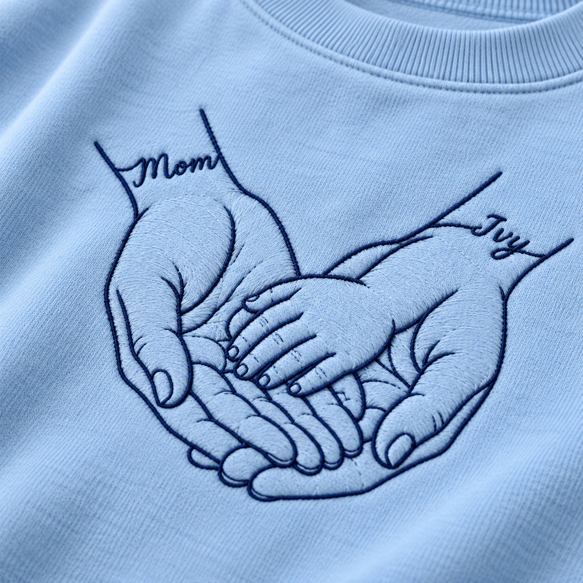 Safe in My Hands personalized Mom hands design; Light Blue sweatshirt mockup, embroidery detail; sample text Mom / Ivy