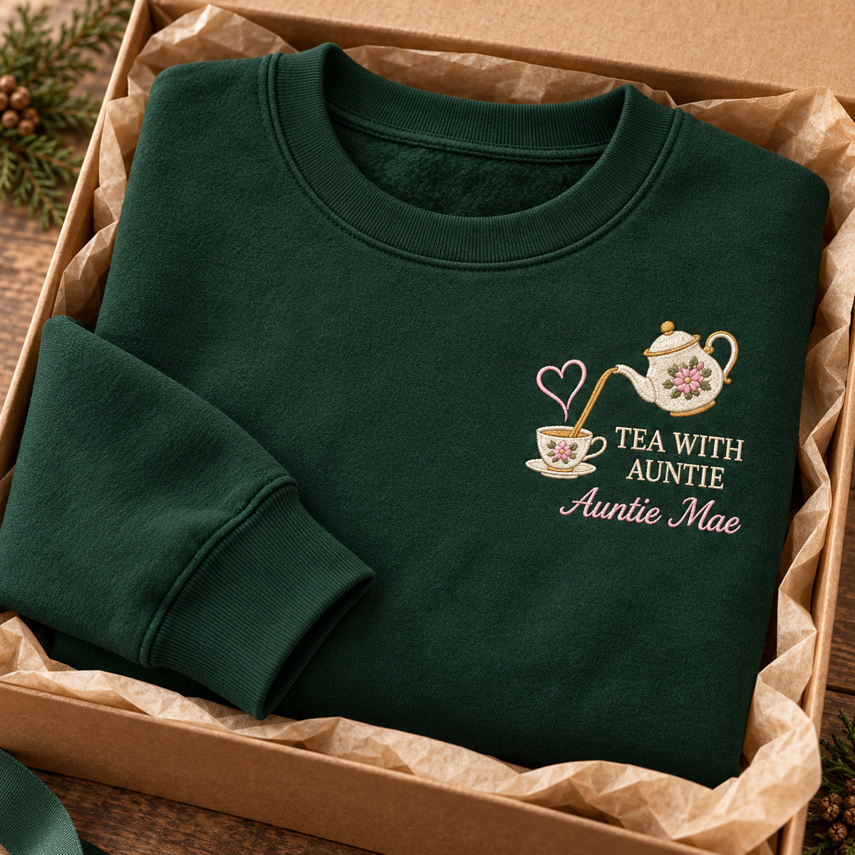 Tea with Auntie sweatshirt concept mockup featuring a floral teapot pouring into a teacup with a heart accent, sample personalization Auntie Mae, personalization view