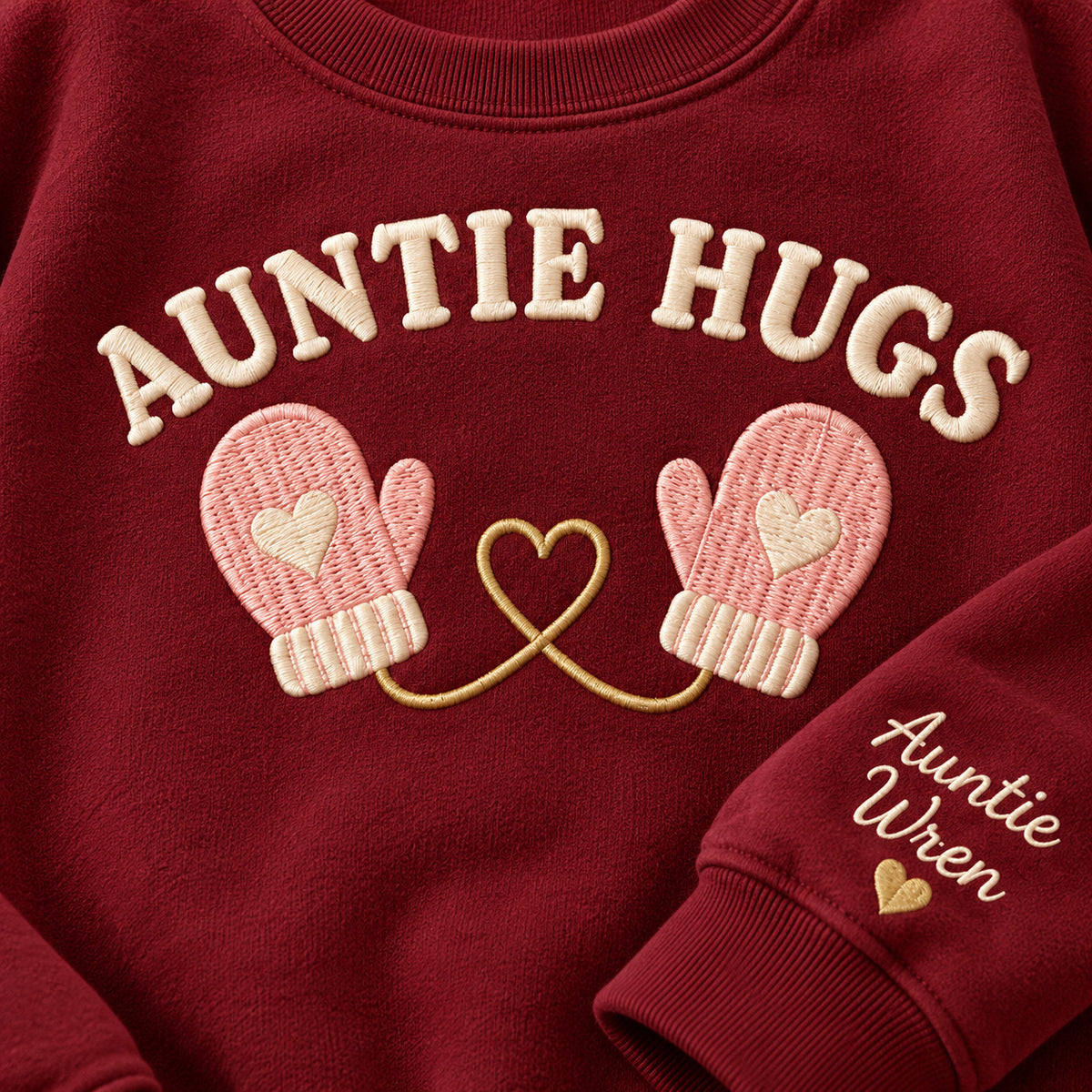 Auntie Hugs sweatshirt concept mockup featuring two mittens linked by a heart-shaped cord, sample personalization Auntie Wren, embroidery view