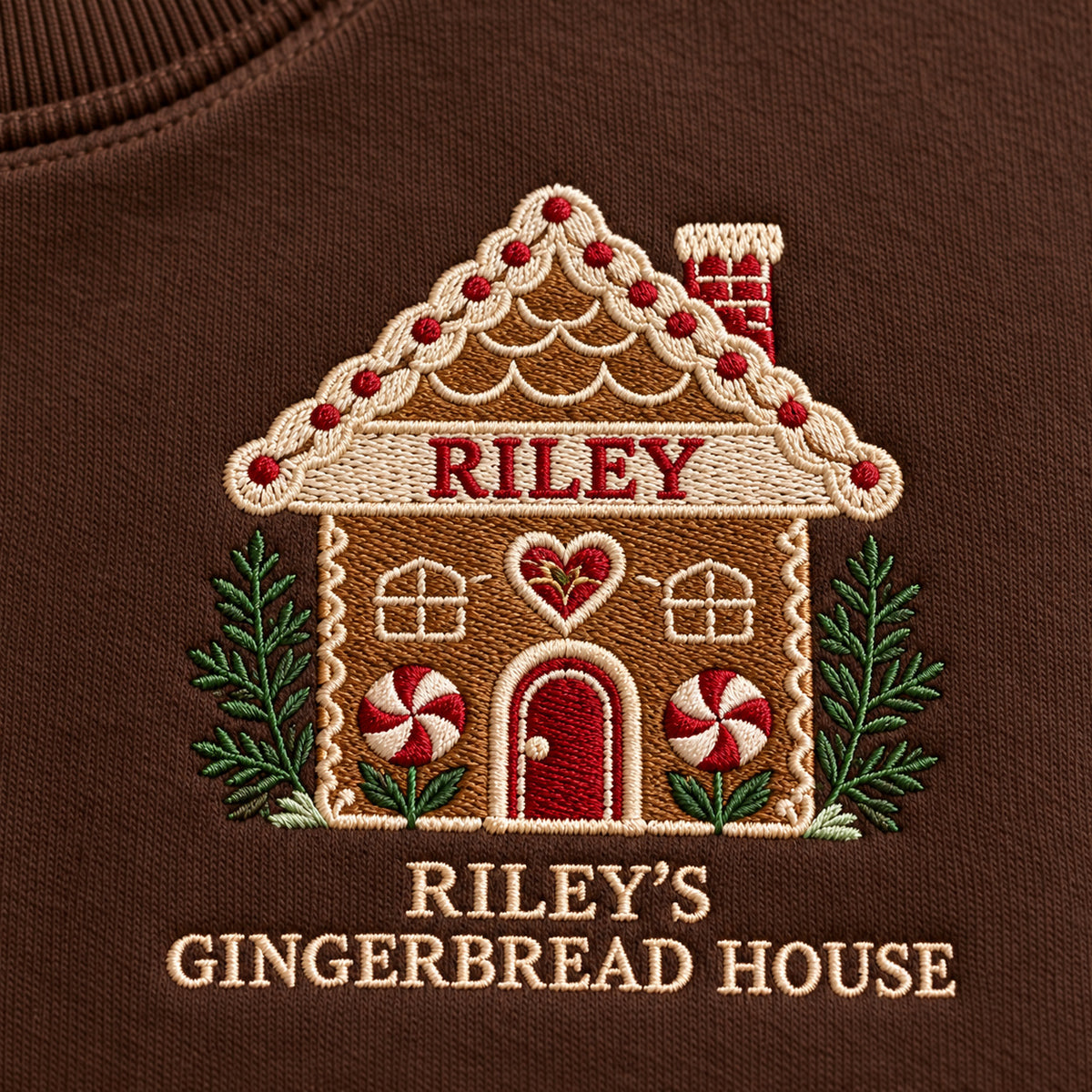 Gingerbread House sweatshirt concept mockup featuring a personalized gingerbread house with candy details, sample personalization RILEY, embroidery view