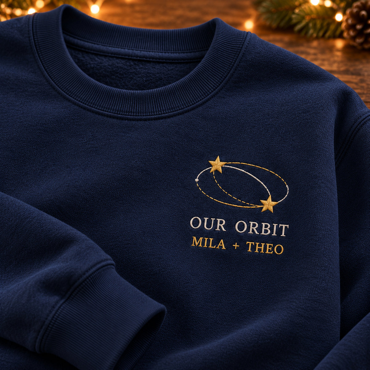Our Orbit sweatshirt concept mockup featuring two stars linked by orbit lines, sample personalization MILA + THEO, embroidery view