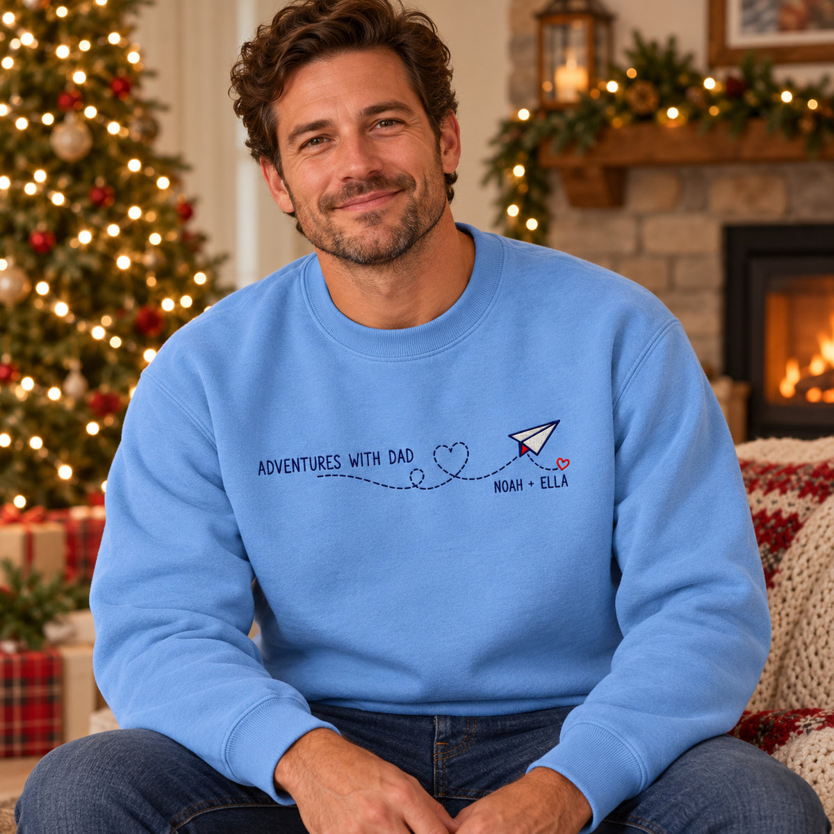Adventures with Dad sweatshirt concept mockup featuring a paper airplane with a heart-shaped flight trail, sample personalization NOAH + ELLA, lifestyle view