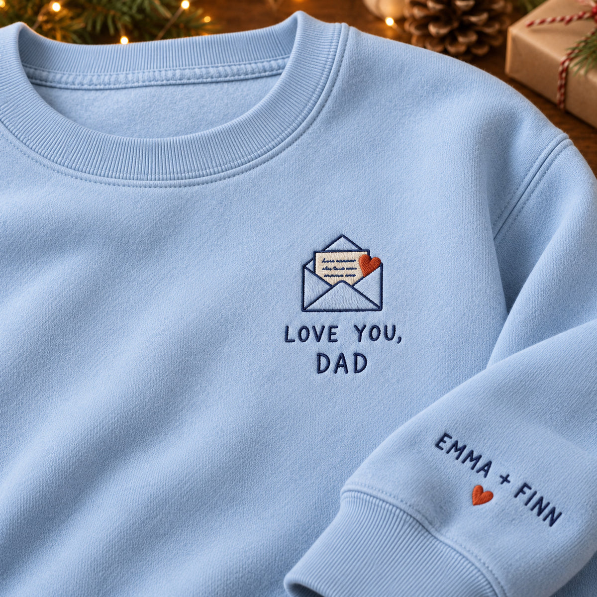 Love You Dad Letter sweatshirt concept mockup featuring a love letter in an envelope with a red heart, sample personalization EMMA + FINN, embroidery view