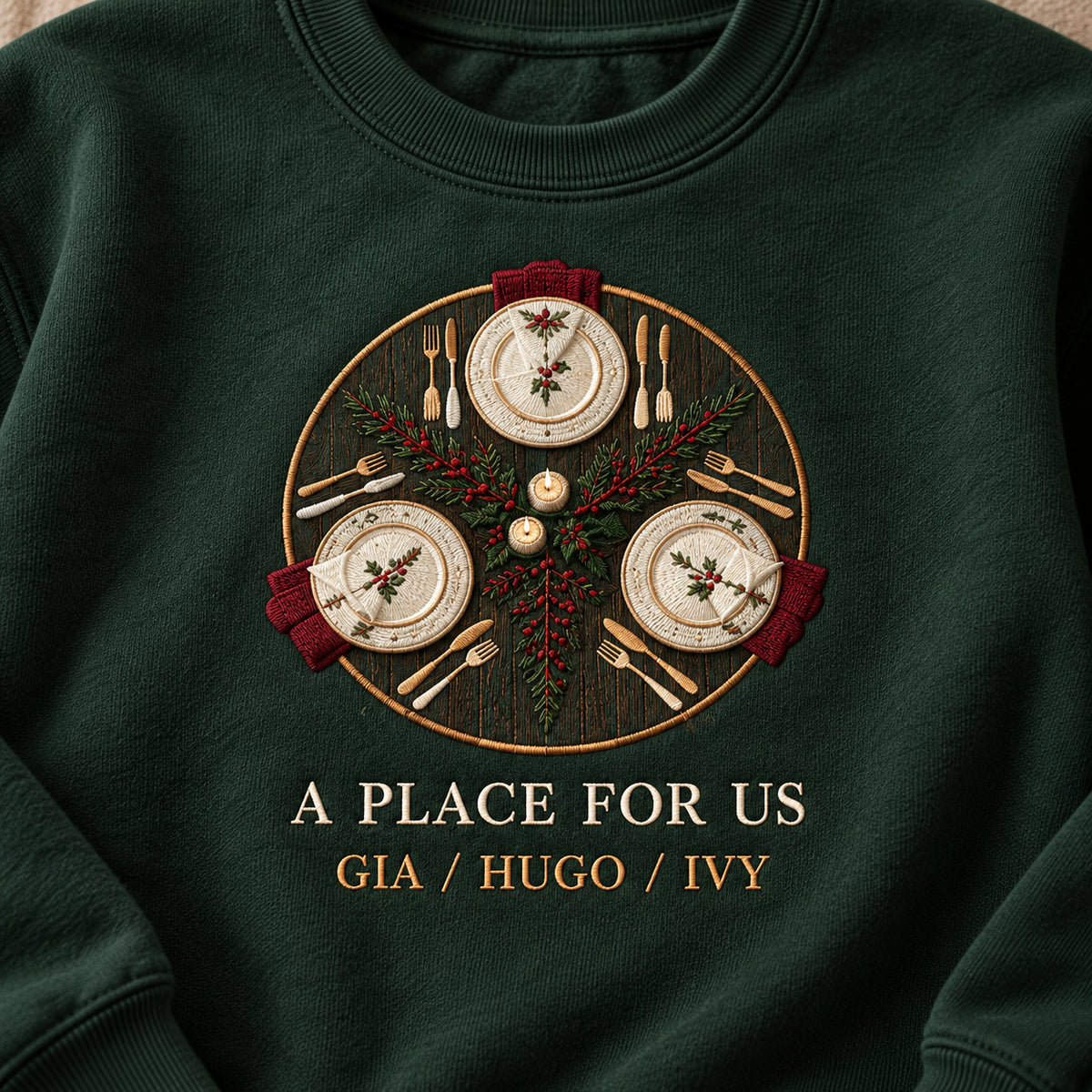 Family Table sweatshirt concept mockup featuring a round table setting with three places and seasonal greenery, sample personalization GIA / HUGO / IVY, embroidery view