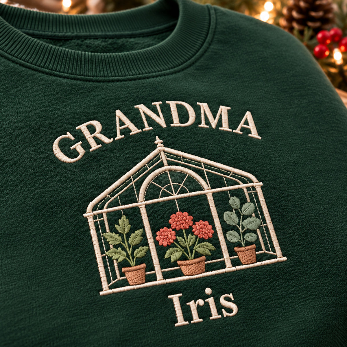 Grandma's Greenhouse sweatshirt concept mockup featuring a greenhouse filled with potted flowers and plants, sample personalization Iris, embroidery view