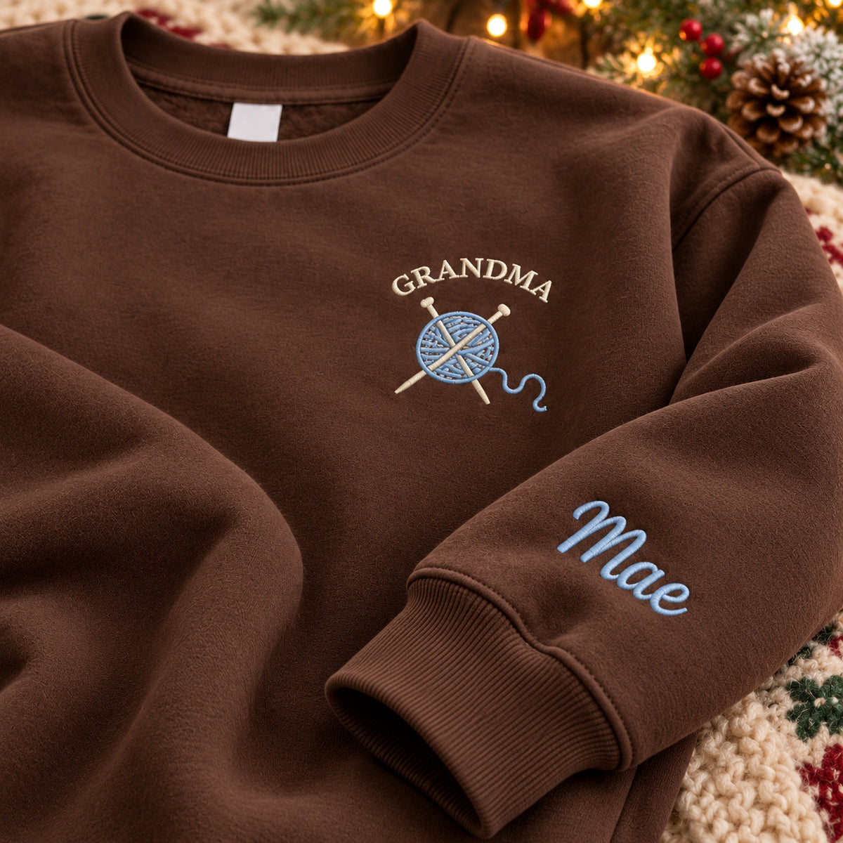 Grandma's Knitting sweatshirt concept mockup featuring a ball of yarn and crossed knitting needles, sample personalization Mae, personalization view