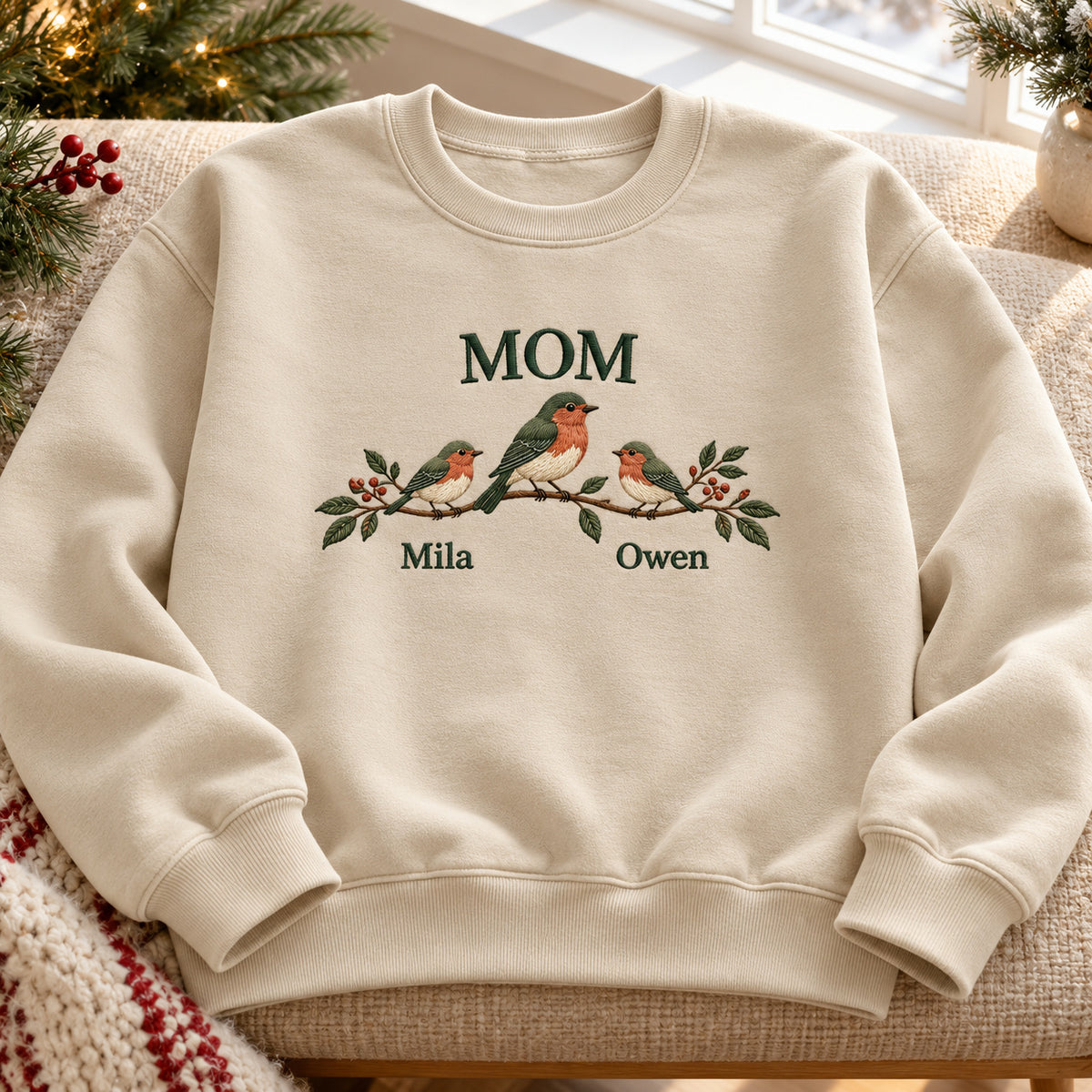 Mother Bird and Little Birds sweatshirt concept mockup featuring a mother bird and two little birds resting on a leafy branch, sample personalization Mila   Owen, hero view