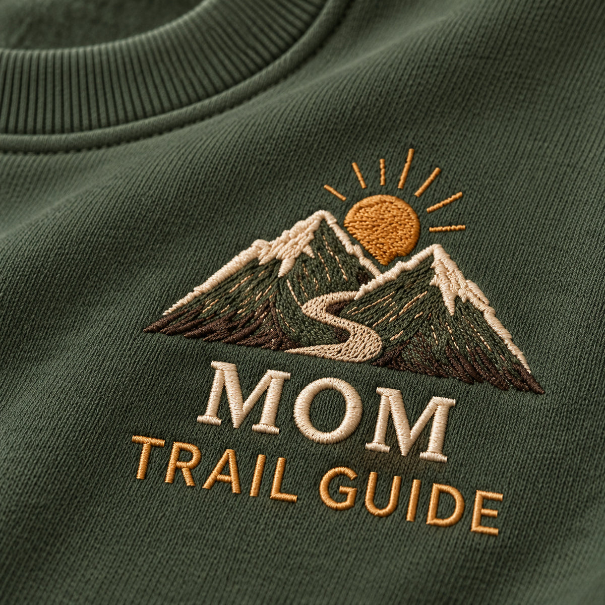 Mom's Adventure Trail sweatshirt concept mockup featuring mountains, a winding trail and a rising sun, sample personalization Hazel, embroidery view