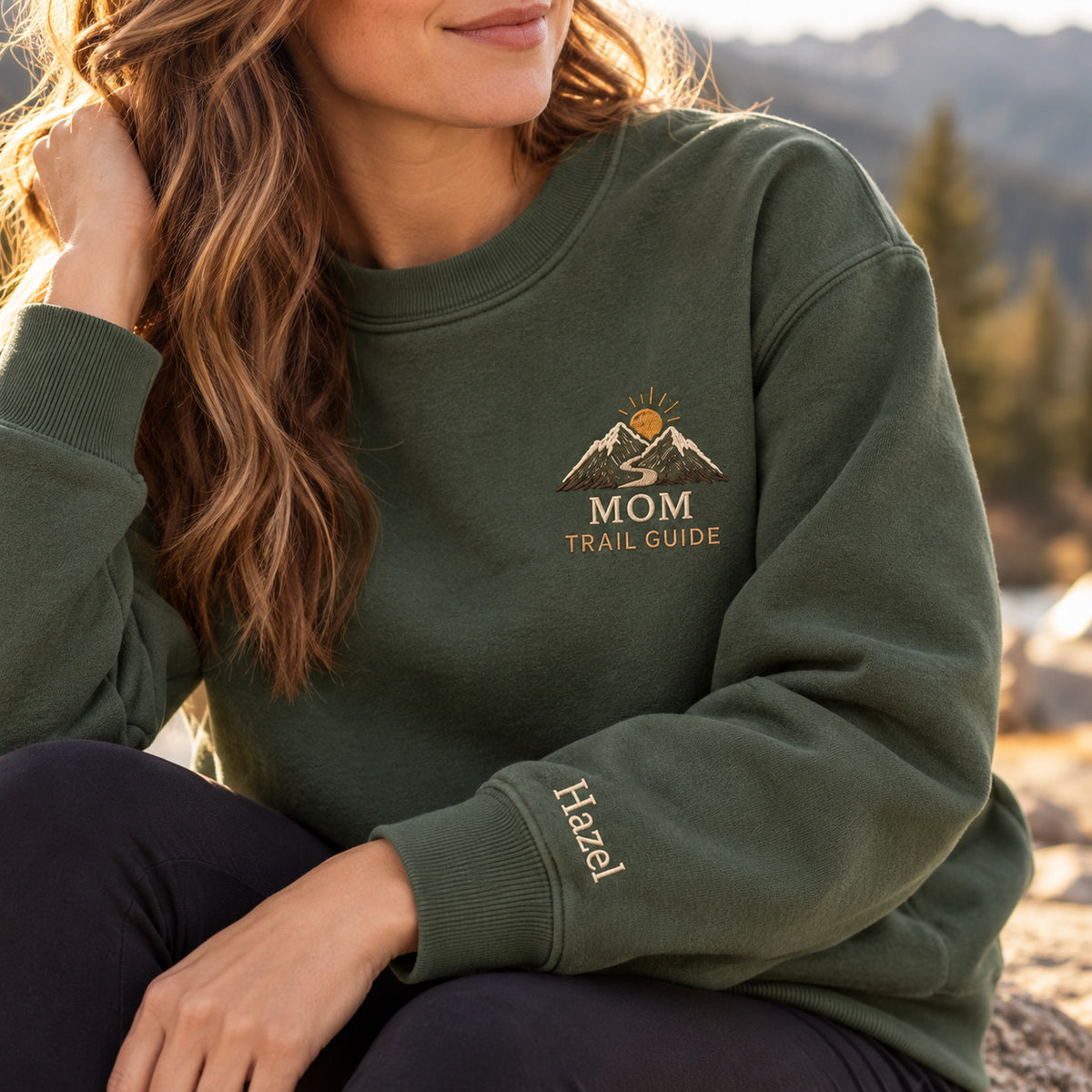 Mom's Adventure Trail sweatshirt concept mockup featuring mountains, a winding trail and a rising sun, sample personalization Hazel, personalization view