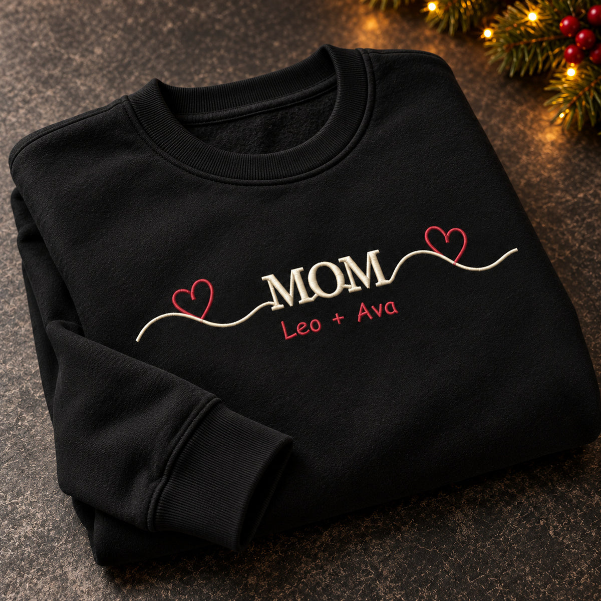 Mom's Heartbeat sweatshirt concept mockup featuring a flowing line connecting two hearts around MOM lettering, sample personalization Leo + Ava, personalization view