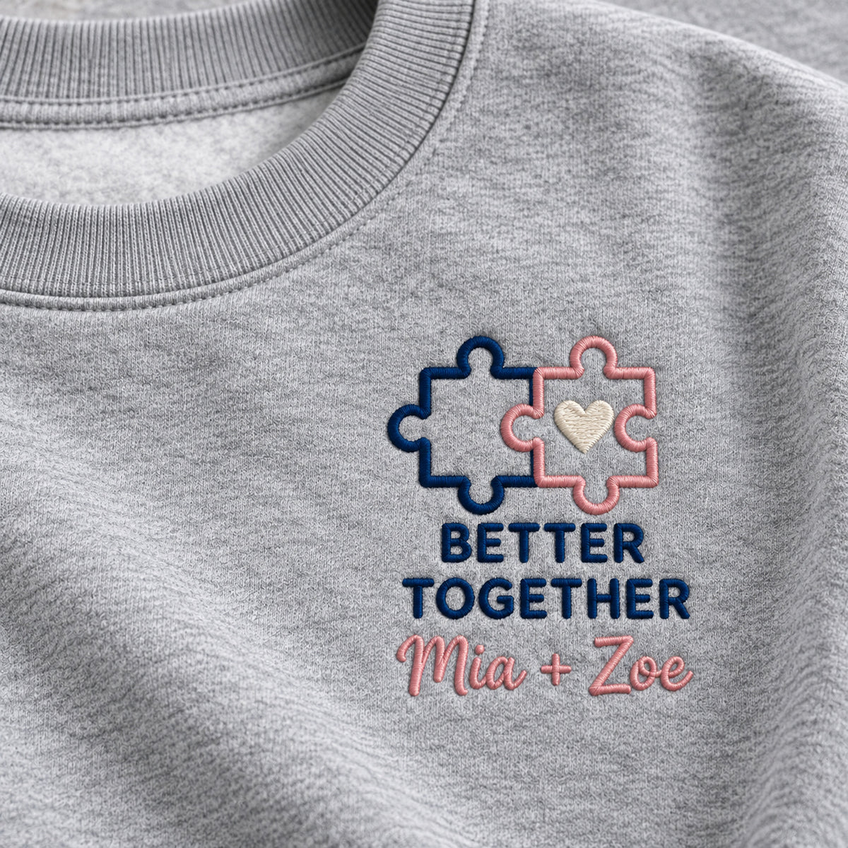 Better Together Sisters sweatshirt concept mockup featuring two connected puzzle pieces with a heart, sample personalization Mia + Zoe, embroidery view
