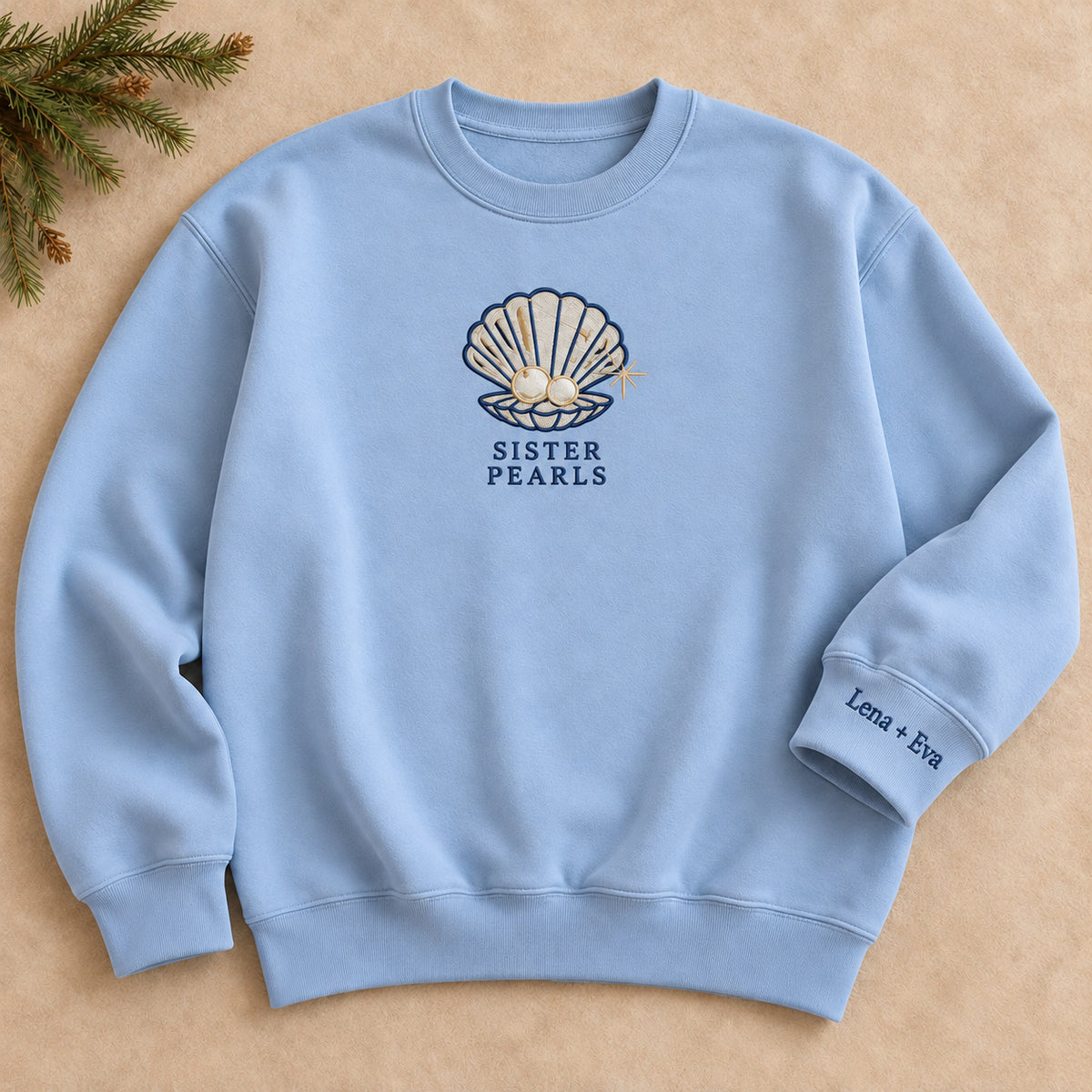 Sister Pearls sweatshirt concept mockup featuring an open seashell holding two pearls, sample personalization Lena + Eva, hero view