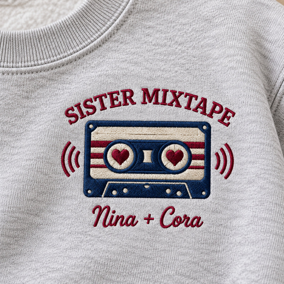 Sister Mixtape sweatshirt concept mockup featuring a cassette tape with heart-shaped reel centers, sample personalization Nina + Cora, embroidery view