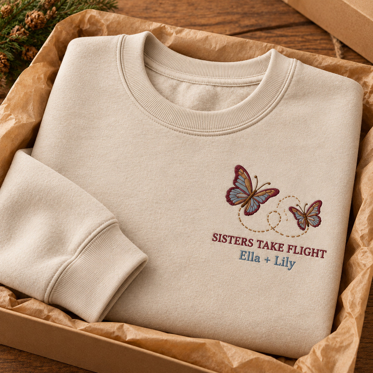 Sisters Take Flight sweatshirt concept mockup featuring two butterflies with a looping flight path, sample personalization Ella + Lily, personalization view