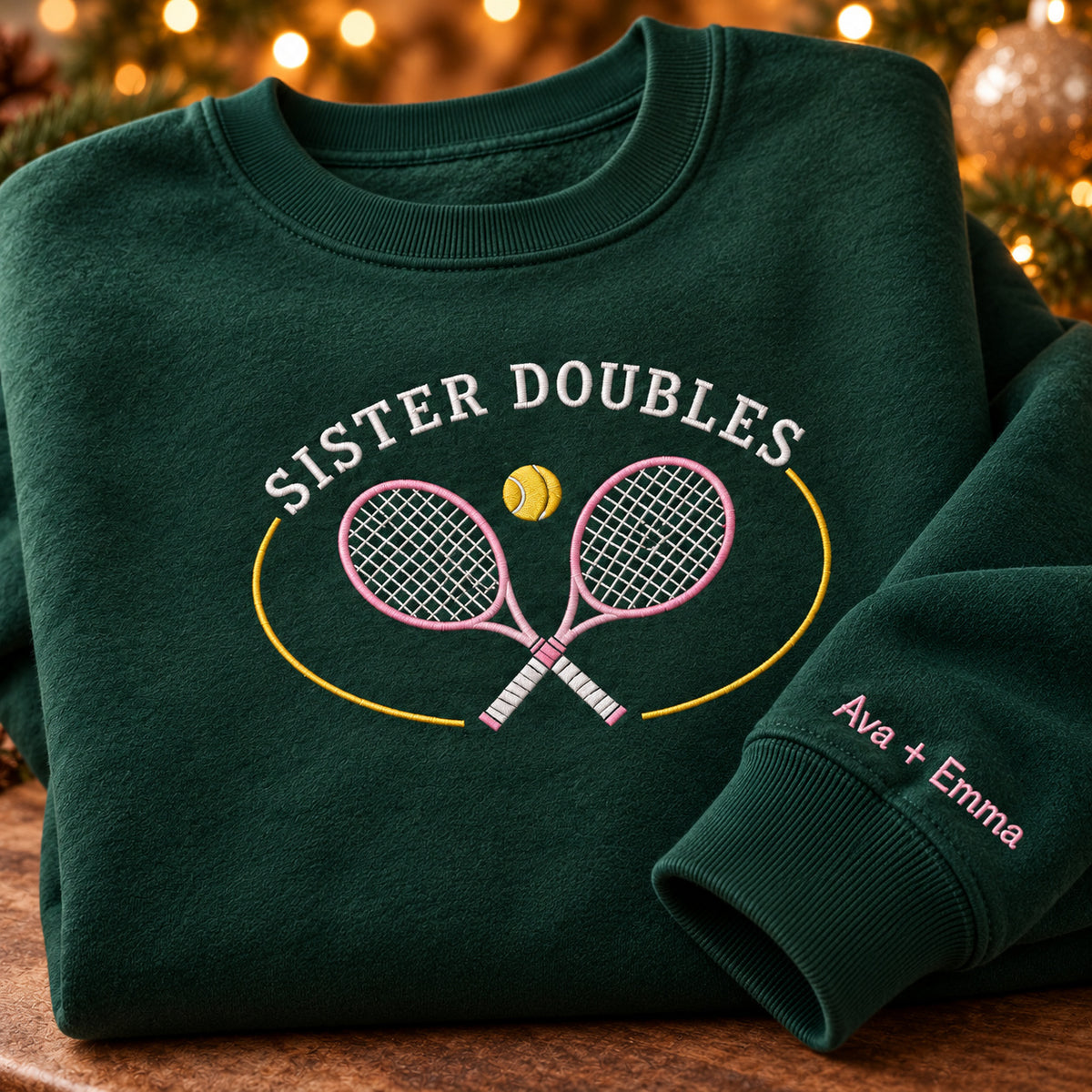 Sister Doubles sweatshirt concept mockup featuring two crossed tennis rackets and a tennis ball, sample personalization Ava + Emma, personalization view